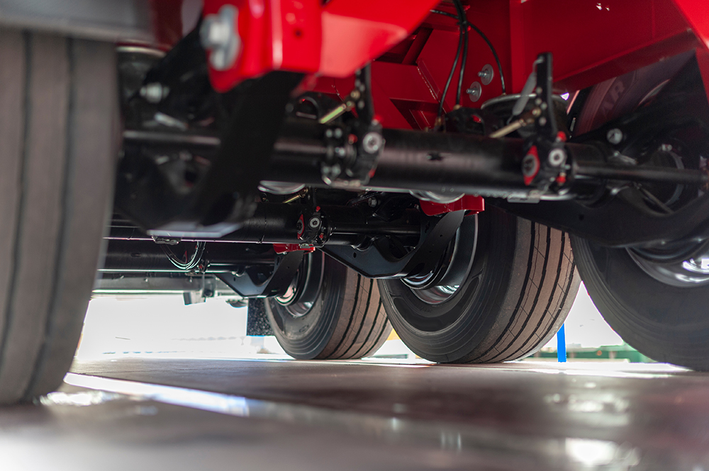 Underneath a New Semi Truck Trailer showing the rear Chassis and Three axles and Wheels with Tyre Treads and Airlines.