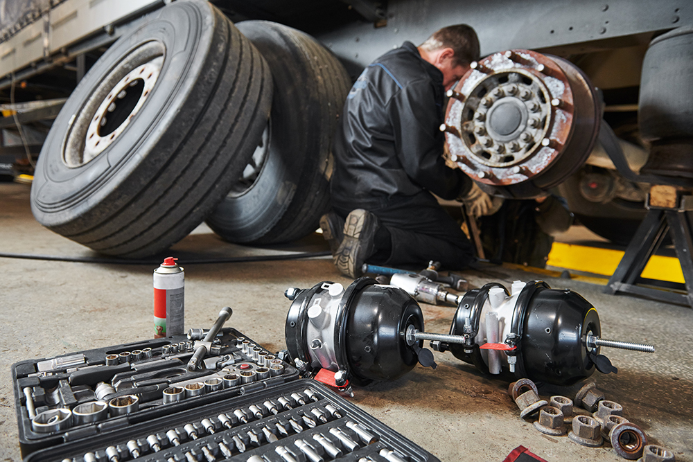 Truck repair service. Mechanic works with brakes in truck workshop