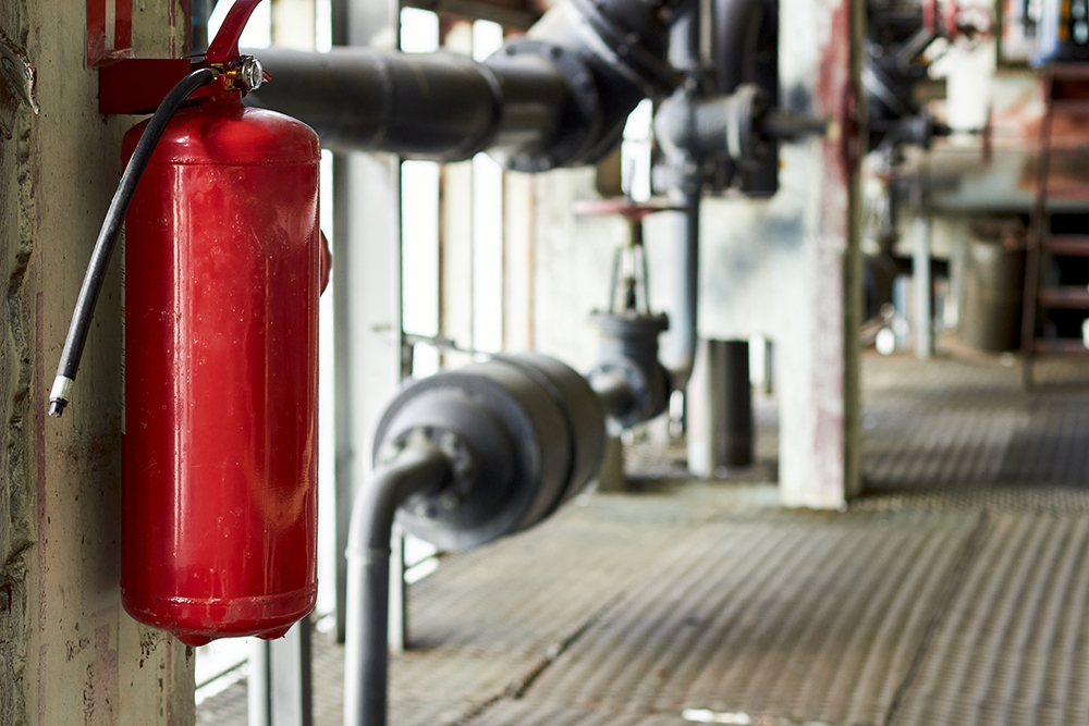 Fire extinguisher security guard equipment in factory for fire protection system. Carbon dioxide fire extinguisher with pressure gauge on wall of production room. Fire safety protection concept.