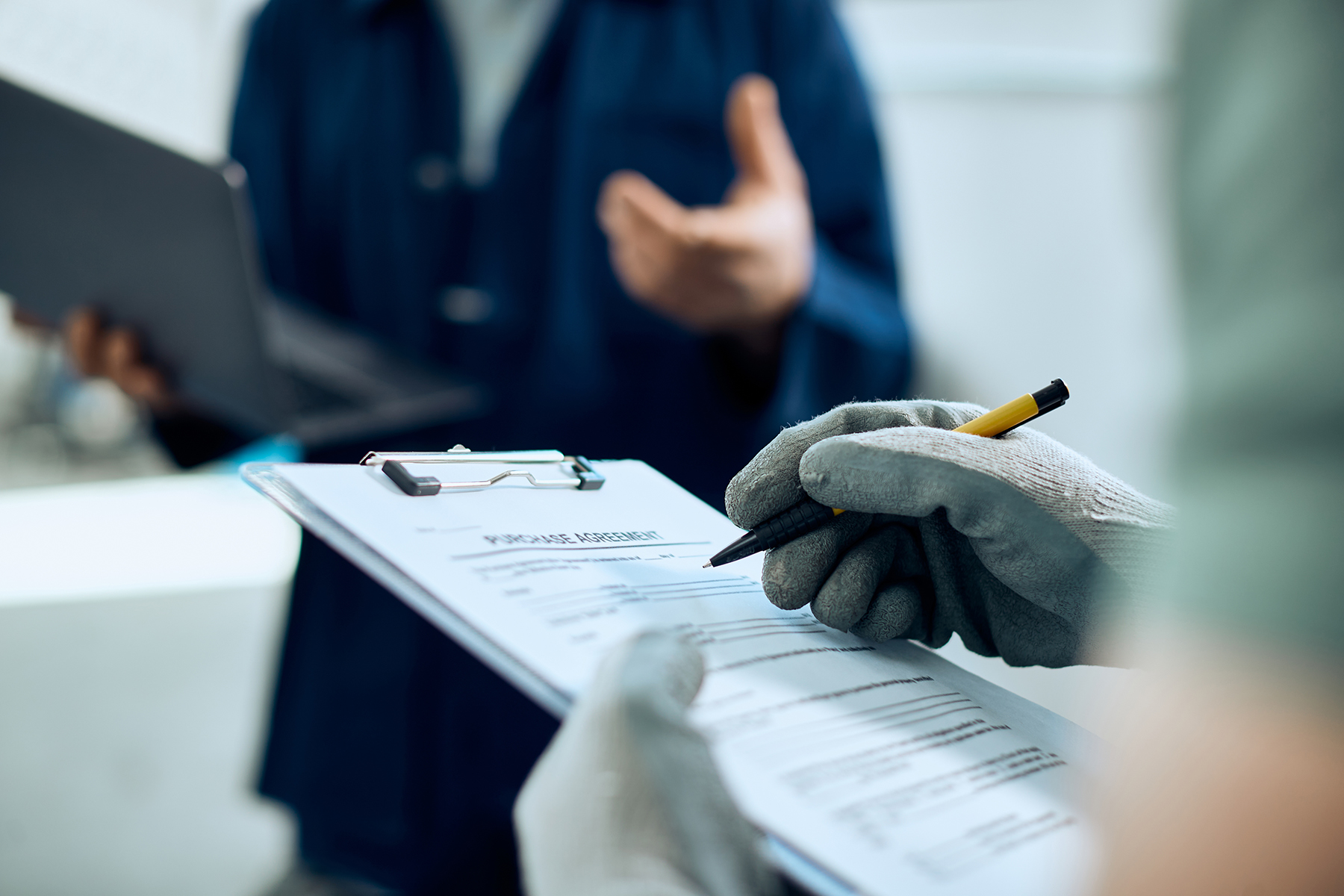 Close-up of mechanic filling police agreement working with auto repair shop manager.